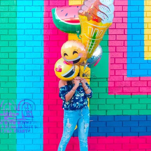 一个小女孩在彩色壁画前用气球庆祝她的生日.